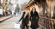 two luxury women walking with shopping bags on a cobblestone road